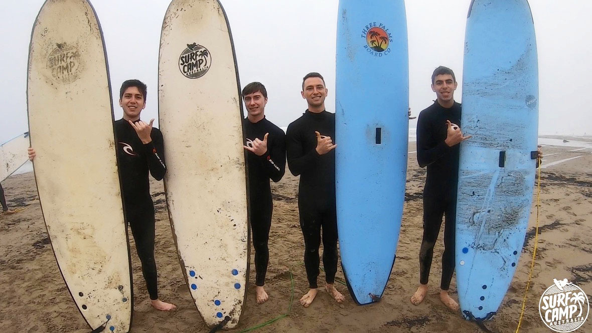 Group of Guys in front of Surfboards